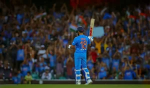 virat kohli in indian cricket team jersey raising his bat after completing a fifty